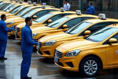 Several taxis being cleaned by a team at once